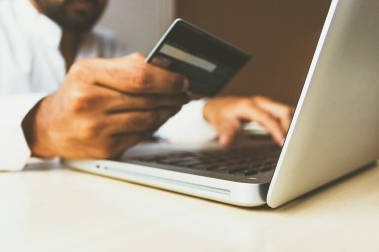 Person nutzt Business-Kreditkarte am Laptop